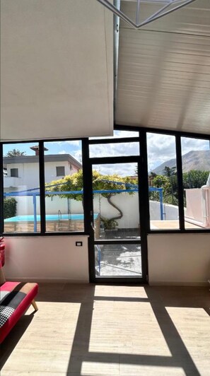 Ein Zimmer mit großen Fenstern, einem Pool und Bergblick.