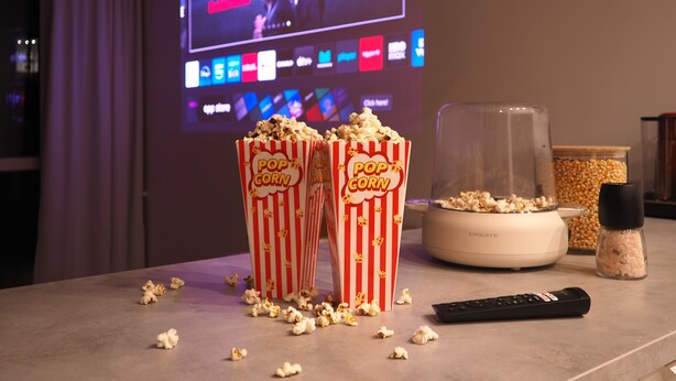 A room with a TV displaying a movie, popcorn in two containers, a remote control, and a popcorn machine. - High standard + private cinema & PS4 + close to Old Town (Warszawa)