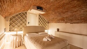 A bedroom with a brick ceiling, a large bed, a bedside table with a lamp, and a wardrobe. - Historic, elegant and modern residence on 3 floors (Verona)