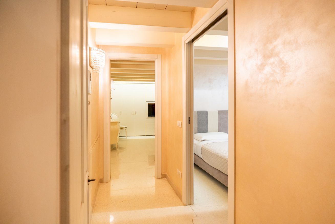 Un couloir étroit mène à une chambre qui contient un lit, un bureau et une chaise.