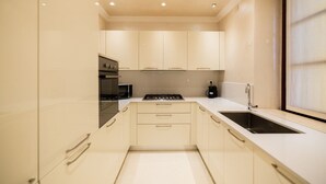 A modern kitchen with white cabinets, a stove, a sink, and a window. - Historic, elegant and modern residence on 3 floors (Verona)