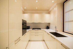 A modern kitchen with white cabinets, a stove, a sink, and a window. - Historic, elegant and modern residence on 3 floors (Verona)