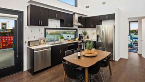 A modern kitchen with dark cabinets, stainless steel appliances, and a dining area with a wooden table and chairs. - New Walk to Gulch - Private Penthouse Pool Deck Views (Nashville)