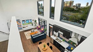 A modern apartment with a kitchen, dining area, and living room, featuring large windows and a city view. - New Walk to Gulch - Private Penthouse Pool Deck Views (Nashville)