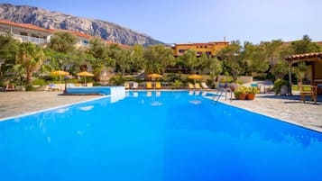 Una piscina al aire libre de temporada, sombrillas