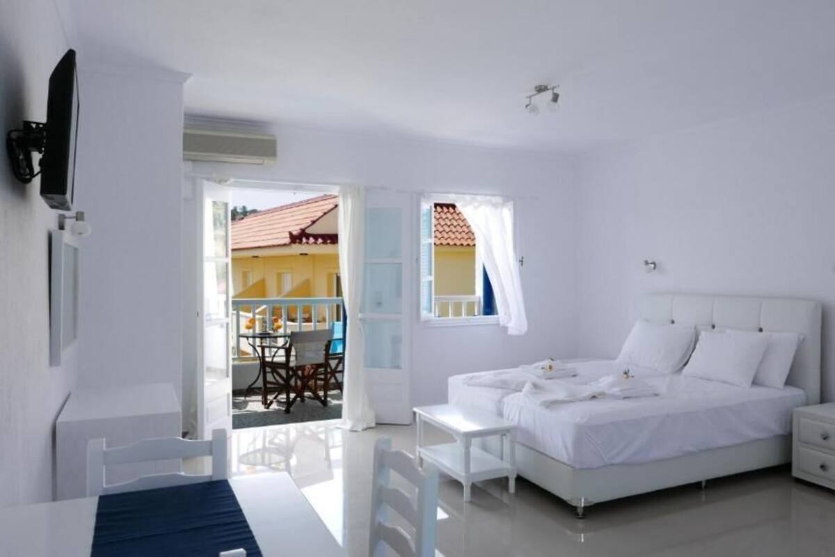 A bedroom with a bed, bedside tables, a TV, and a balcony with a view.