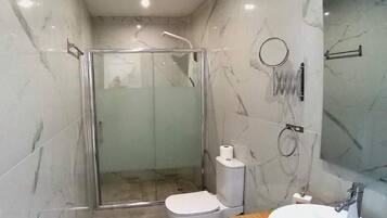 A modern bathroom with a glass-enclosed shower, a toilet, and a sink with a mirror.