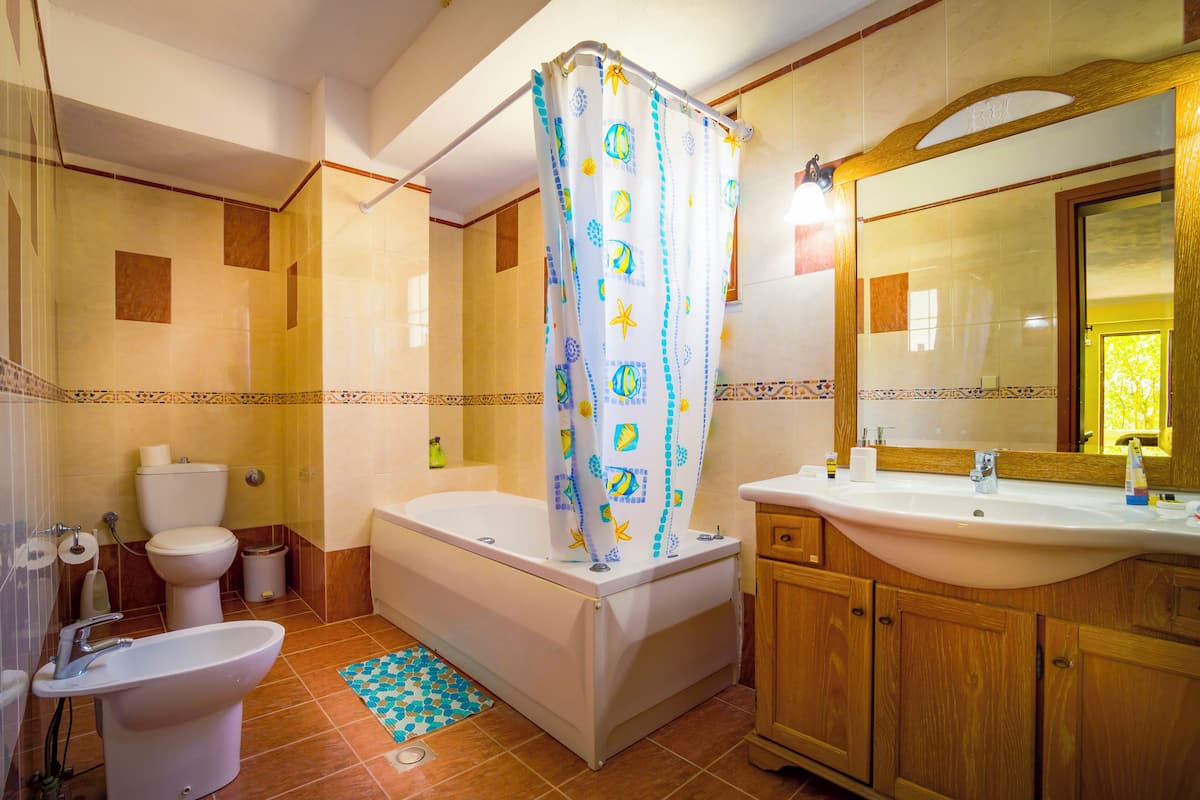A bathroom with a bathtub, toilet, sink, and a shower curtain.