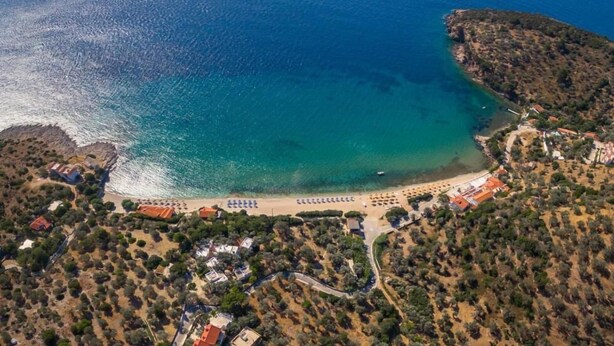 Vista aérea de una zona costera con playa, villas y una piscina.