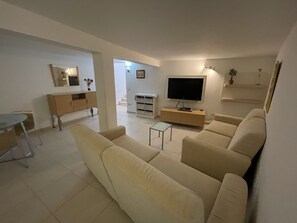 Ein Wohnzimmer mit einer Couch, einem Fernseher und einem kleinen Tisch.