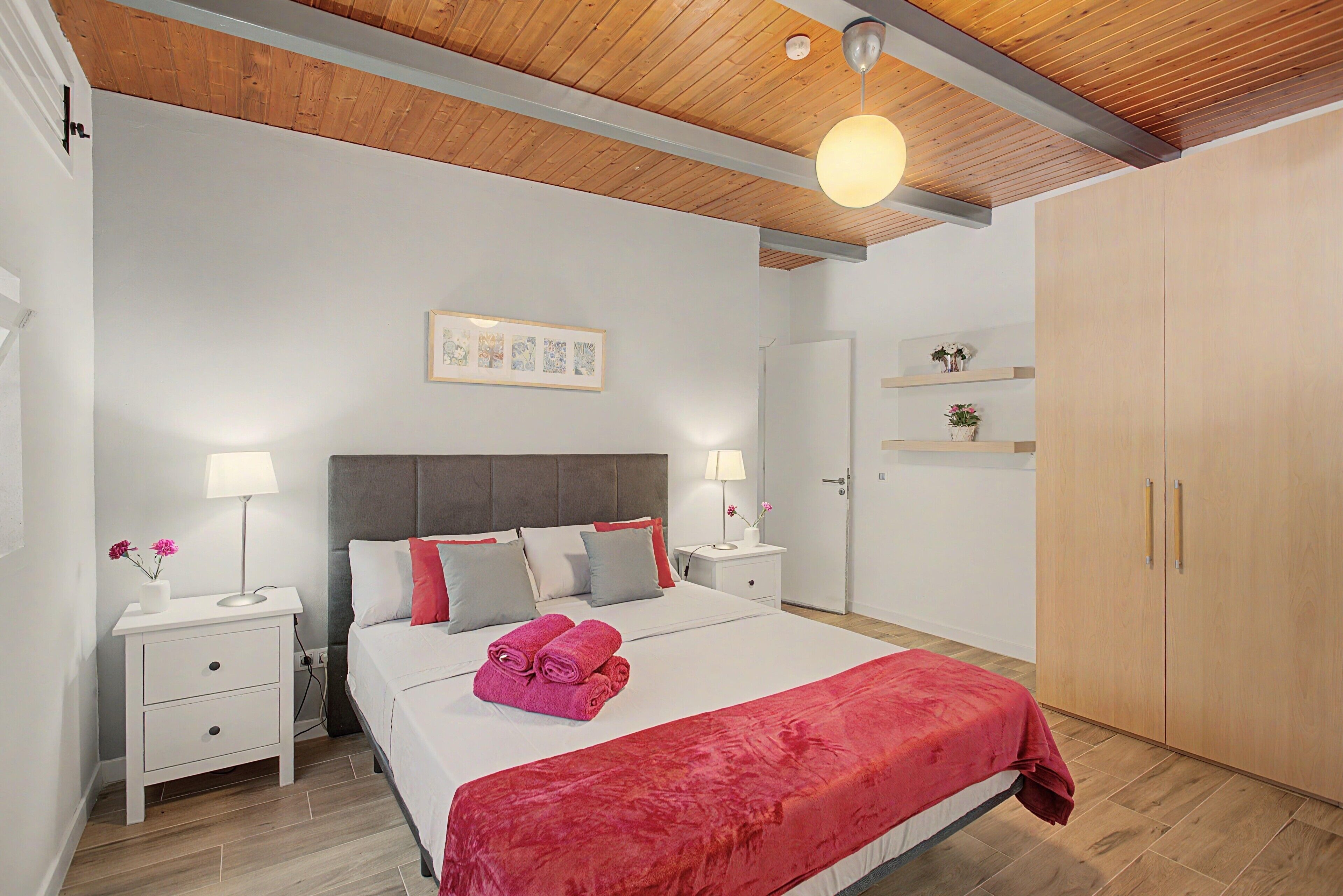 Ein Schlafzimmer mit einem Bett, Nachttischen, einem Schrank und einer Deckenleuchte.