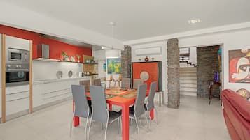 Una cocina moderna con electrodomésticos integrados y un comedor con una mesa roja y sillas grises.