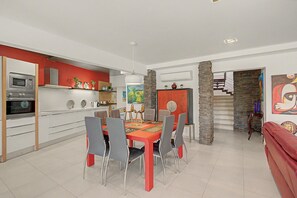 Une cuisine moderne dotée d’appareils électroménagers intégrés et d’un coin repas avec une table rouge et des chaises grises.