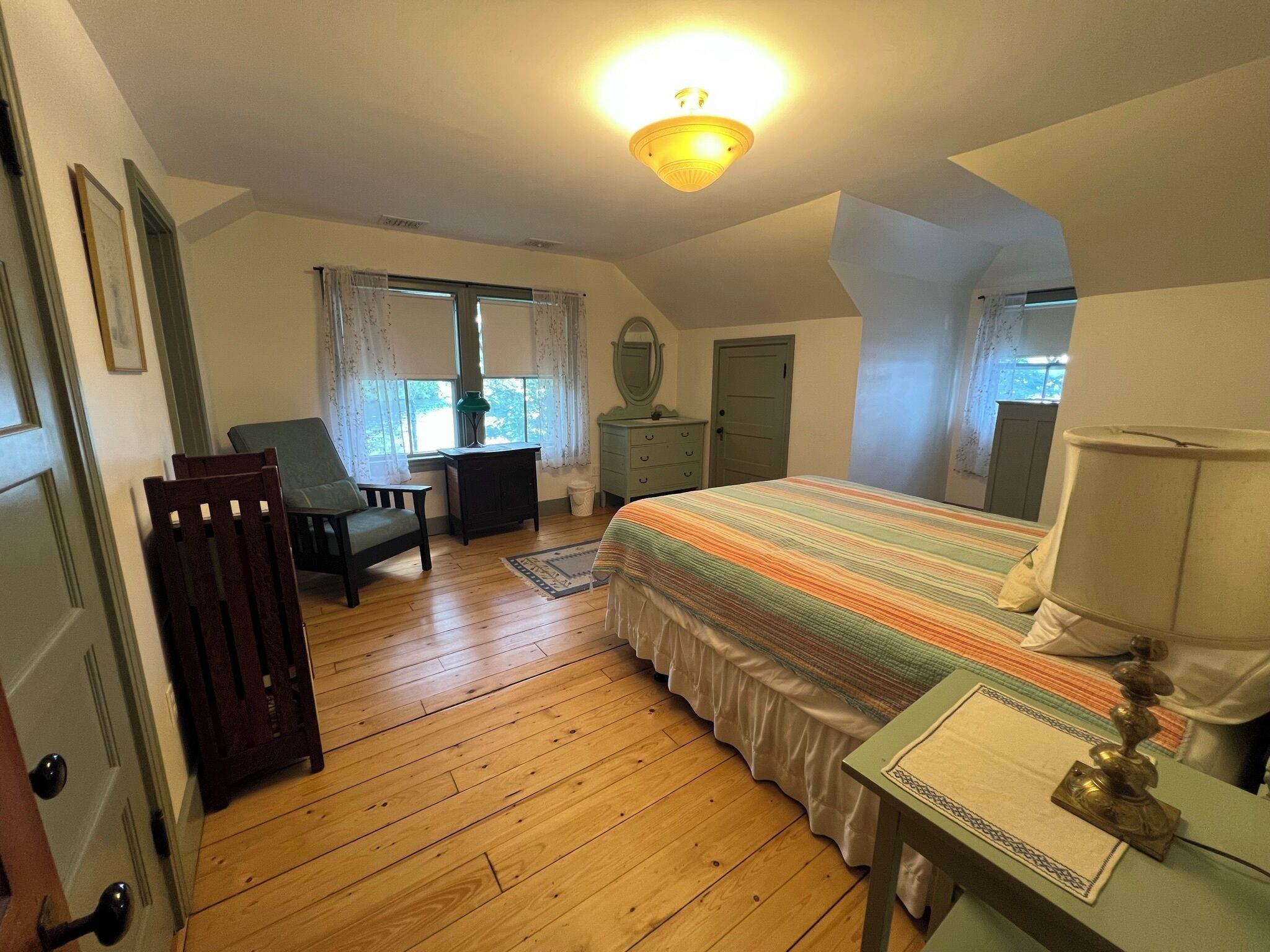Een slaapkamer met een bed, een bureau, een stoel, een kast en een raam.