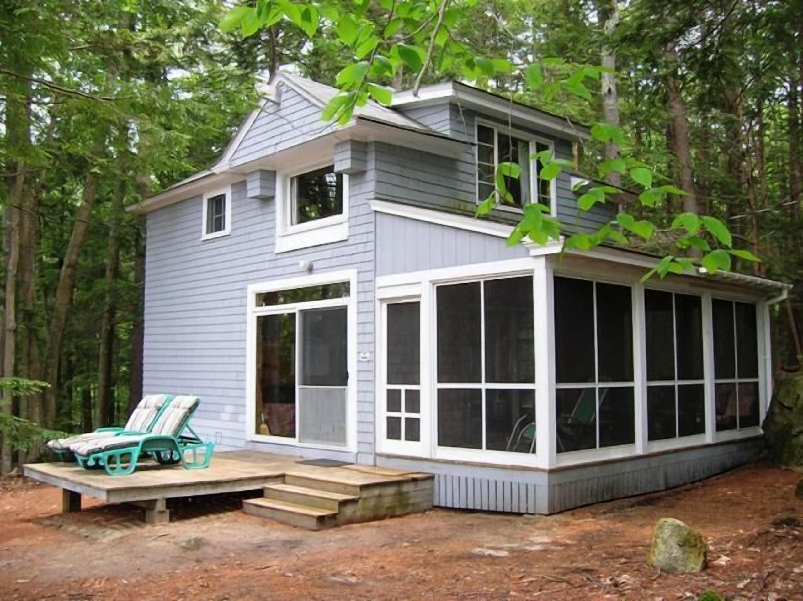 Una casa pequeña con un porche, una zona cubierta con ventanas y un conjunto de escalones que suben al porche.