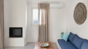 Ein modernes Wohnzimmer mit einem Holzesstisch, einem an der Wand montierten Fernseher, einer Couch und einem Fenster mit Vorhängen.
