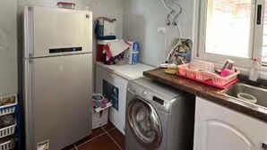 Kompakti keittiö, jossa on jääkaappi, pesukone ja pieni tiskiallas.