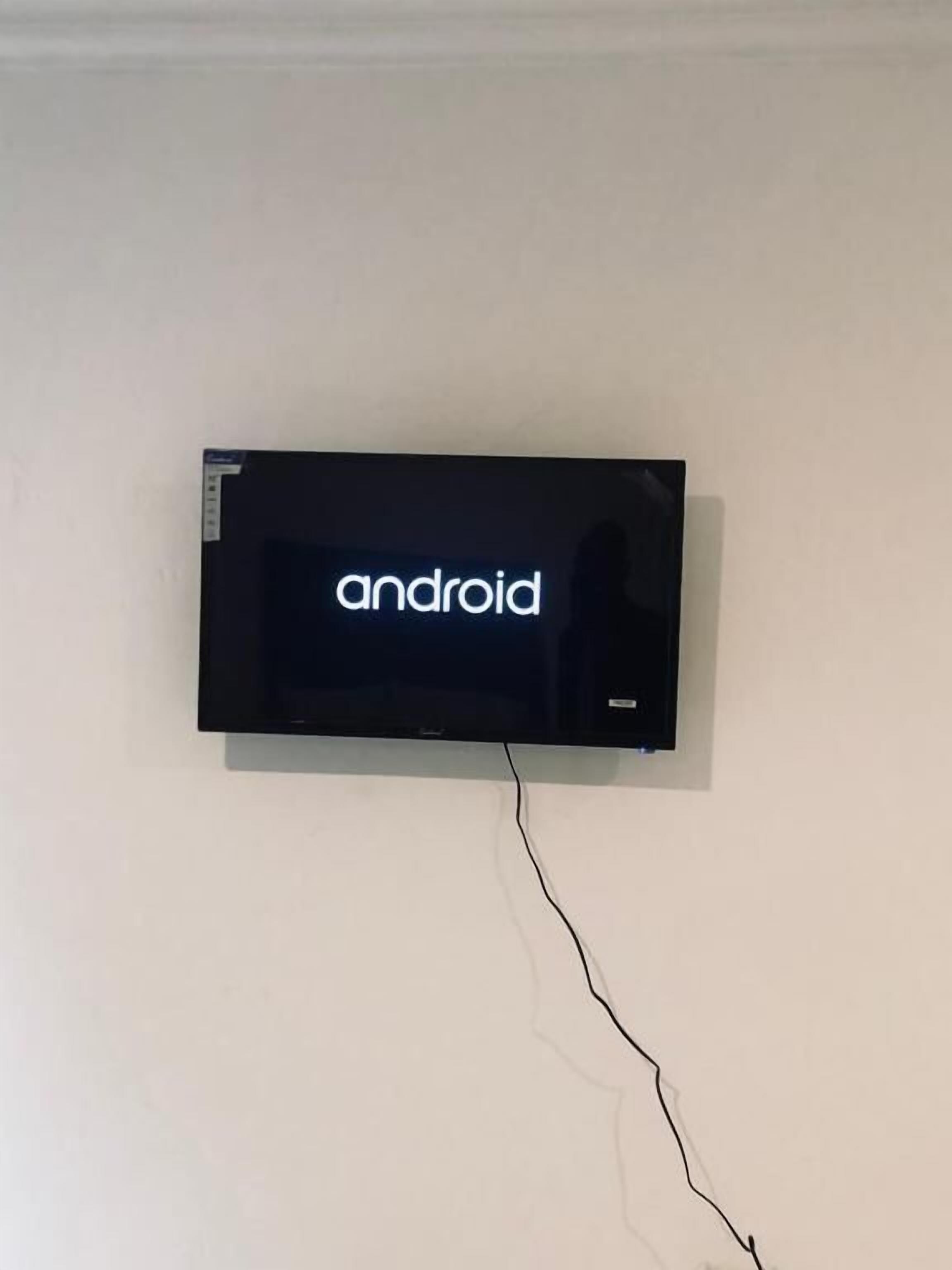 A flat-screen TV mounted on a white wall with a visible power cord.