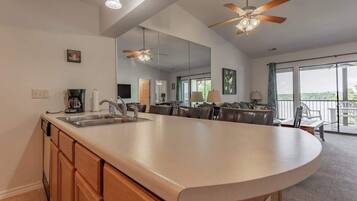 A kitchen with a central island, a dining area with chairs, a ceiling fan, and a large window.
