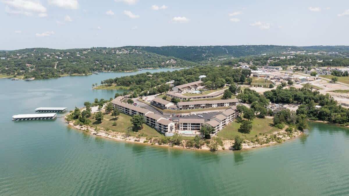 An aerial view of a hotel with a large building surrounded by water, a dock, and a boat.