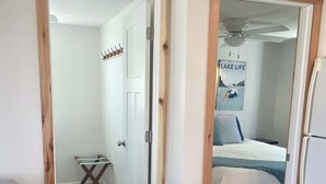 A bedroom with a bed, a ceiling fan, and a poster on the wall. - Cozy Cottage - Lakeview (Reeds Spring)