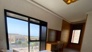 A bedroom with a large bed, a desk, and a view of the outside. - Magnificent Duplex Sea View in Taghazout Bay (Taghazout)