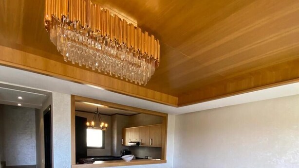 A modern living room with a sectional sofa, a glass coffee table, and a unique wooden chandelier. - Magnificent Duplex Sea View in Taghazout Bay (Taghazout)