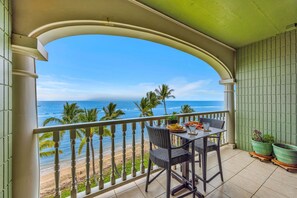 A balcony with a view of the beach and ocean, a table with chairs, and potted plants. - SUMMER SALE! Direct Oceanfront Studio with Lanai & Sunset Views -Lahaina Shores 631 (Lahaina)