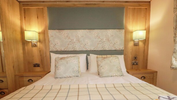 A bed with a plaid bedspread, two pillows, and two bedside lamps. - 8 Summerleaze (Bude)
