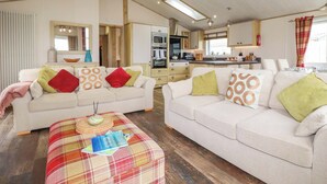 A spacious living area with two sofas, a coffee table, a kitchen in the background, and a skylight. - 8 Summerleaze (Bude)