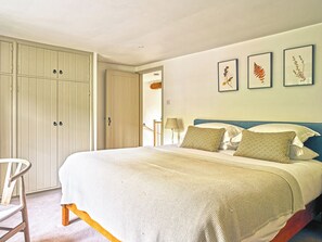 A bedroom with a bed, a chair, and a wardrobe. - Gitcombe Coach House (Totnes)