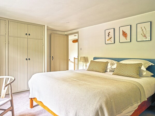 A bedroom with a bed, a chair, and a wardrobe. - Gitcombe Coach House (Totnes)