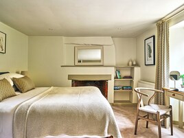 Un dormitorio con cama, una silla, un escritorio, una chimenea y un espejo.