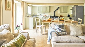 A living room with a sofa, a coffee table, and a dining area with chairs and a table. - Gitcombe Coach House (Totnes)