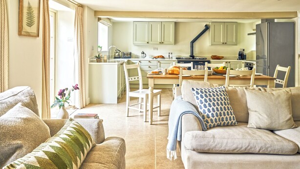 Una sala de estar con un sofá, una mesa de centro y una zona de comedor con sillas y una mesa.