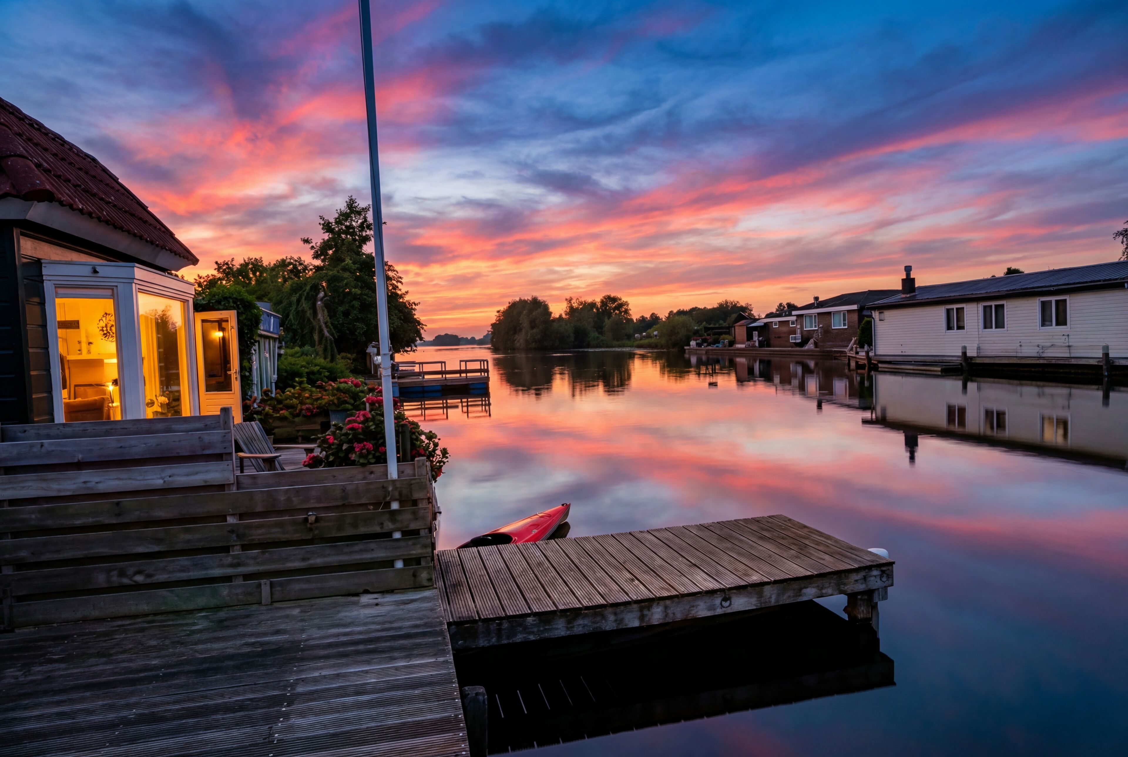 A waterfront property with a dock, a wooden bench, and a kayak.