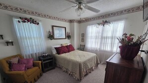 A bedroom with a bed, a nightstand, a dresser, a chair, and a window with curtains. - This cozy 3 bed 2 bath house will remind you of a weekend at Grandmother's. (Albertville)