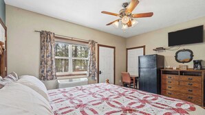 A bedroom with a bed, a ceiling fan, a window with curtains, a dresser, and a television mounted on the wall. - Quail Cove 9 Lakefront Studio Boat Slip Optional (Shell Knob)