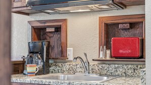A kitchen with granite countertops, a stainless steel sink, wooden cabinets, a red appliance, and a coffee maker. - Quail Cove 9 Lakefront Studio Boat Slip Optional (Shell Knob)
