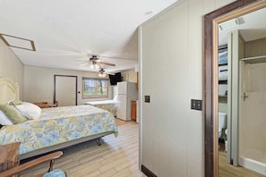 Une chambre à coucher avec un lit, un ventilateur de plafond, une fenêtre et une vue sur l’extérieur.
