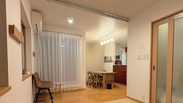 A modern interior with a tatami mat floor, a dining area with a wooden table and chairs, and a sliding glass door leading to a kitchen area. - Perfect Base for Families - 3Bedrooms, 2Baths, Full-Kitchen, Free-P (大阪市)