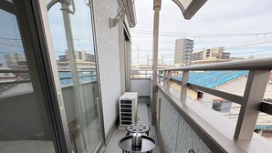 A balcony with a glass door, a metal railing, and a small table with chairs. - Perfect Base for Families - 3Bedrooms, 2Baths, Full-Kitchen, Free-P (大阪市)