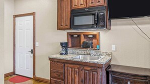 Una cocina compacta con armarios de madera, microondas, cafetera y pileta.