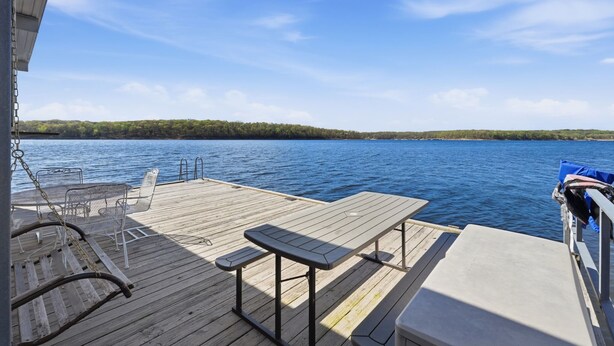 A wooden deck with a table and chairs, overlooking a calm lake. - Quail Cove 6 Lakefront Studio Boat Slip Optional (Shell Knob)