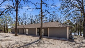 A single-story building with a flat roof, surrounded by trees and a gravel driveway.