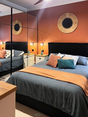 Ein Schlafzimmer mit einem großen Bett, Nachttischen, einem Spiegel und Wandleuchten.