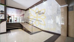Een hotel lobby met marmeren vloeren, een trap en een groot bloemenpatroon aan de muur.