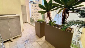 En balkon med flisegulv, et skab og to plantekasser med planter.