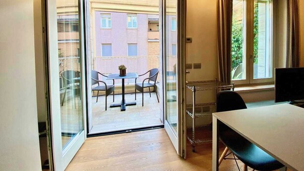 Et værelse med en skydedør, der fører ud til en balkon med et bord og stole.