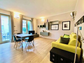 A modern living room with a dining area, a yellow sofa, and a black ottoman. - Luxury 2bed-2bath in top location (Milano)